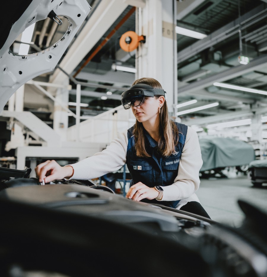 BMW employee uses a HoloLens 2 while working on a BMW engine.