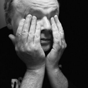 Peyton poses in a black and white dramatization with his head in his hands.