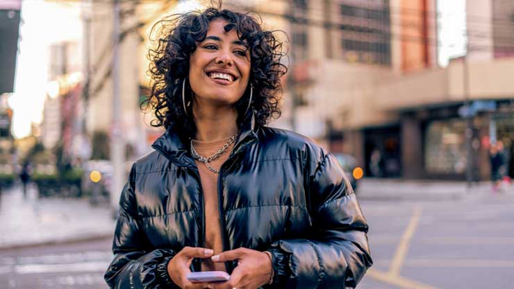 Woman smiling with a phone in her hand in the city.