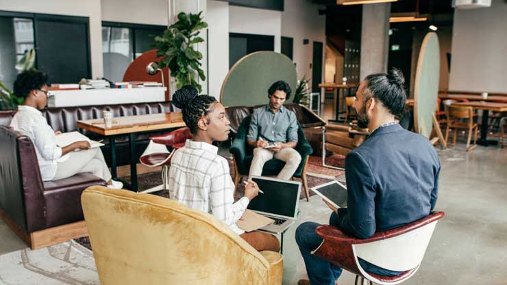 Four Entrepreneurs at work in a common area of a creative workplace